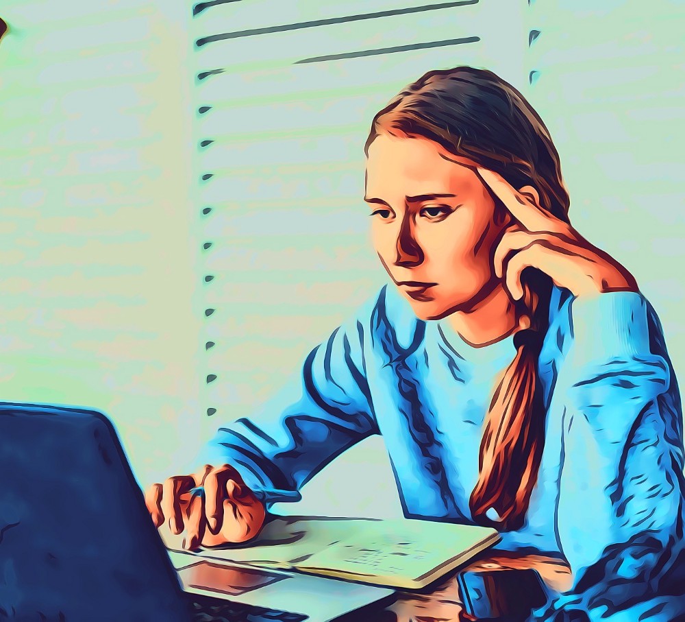 Woman taking physical notes, while looking at her laptop